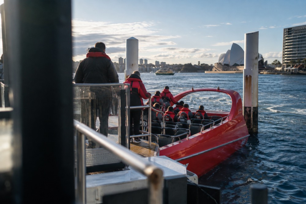 A jet boat at a Circular Quay wharf with riders in life jackets boarding