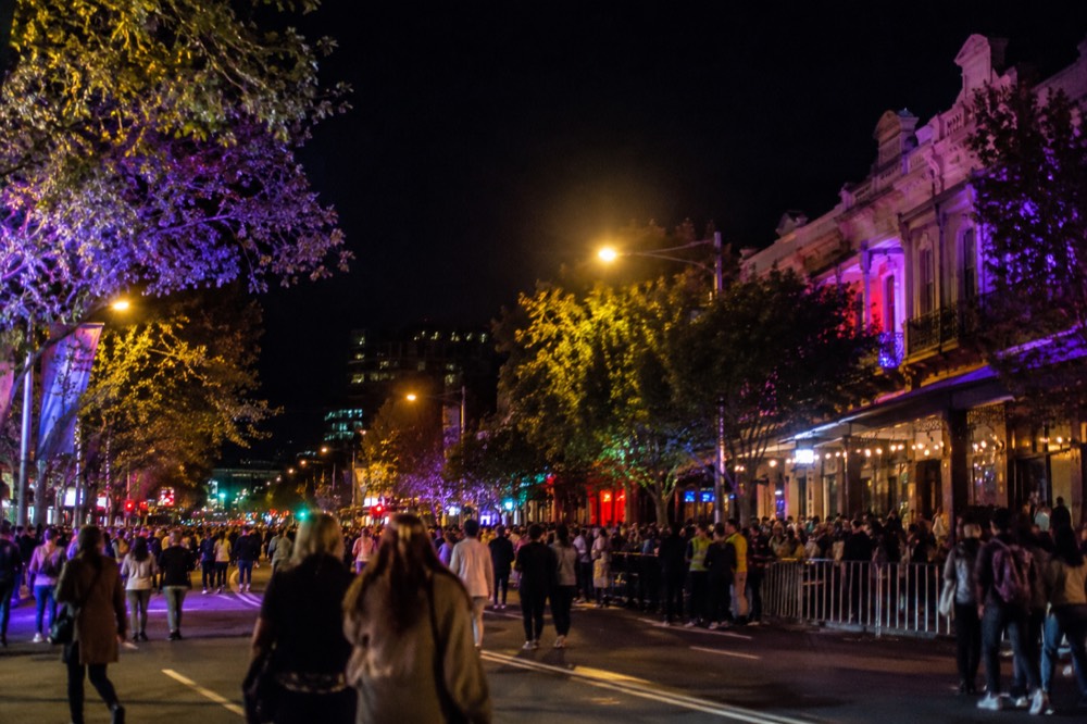 Oxford Street in Sydney lit up at night with colourful lights and crowds along the parade route