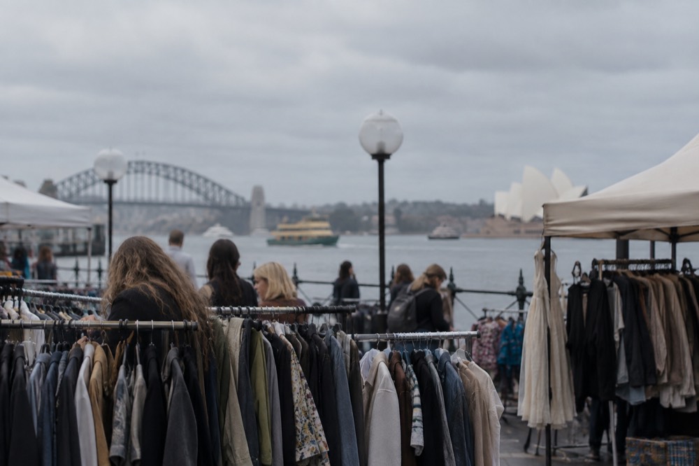Racks of second-hand clothing at an open-air market