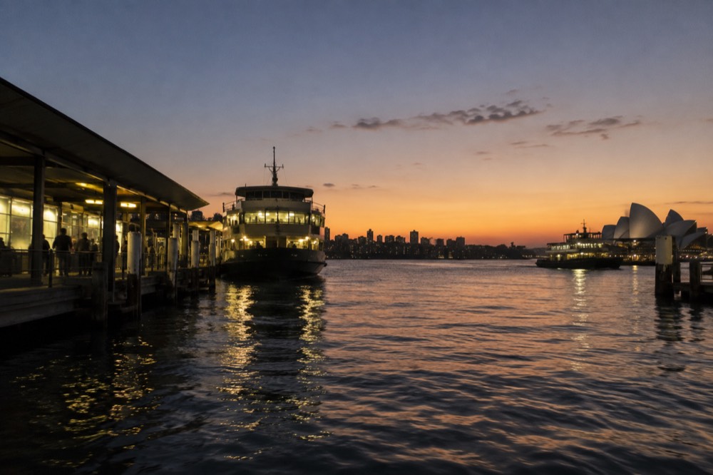 Sydney Harbour at dusk with ferry lights reflecting on calm water