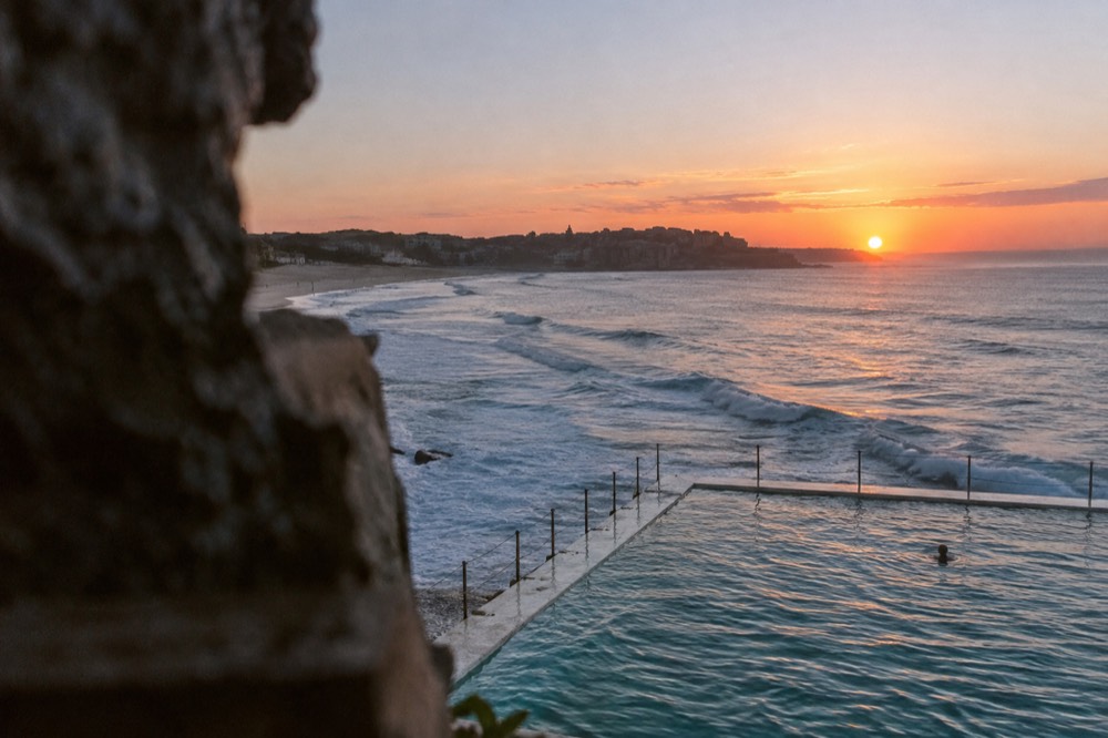 Sunrise over Bondi Icebergs ocean pool with pink light reflecting on calm water