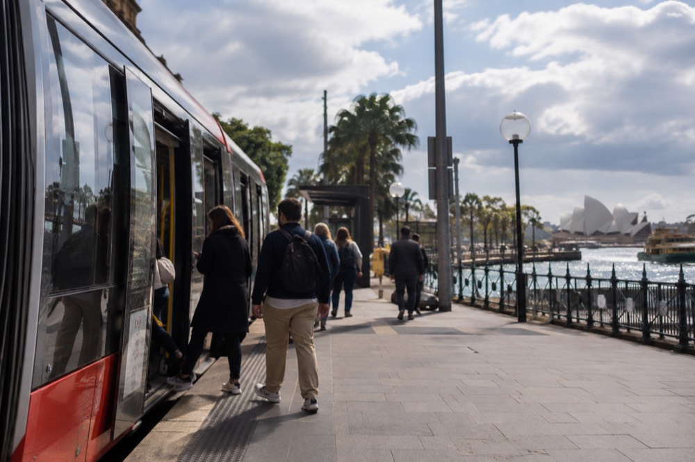 Commuters boarding a light rail tram on a city street