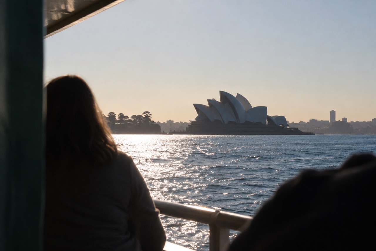 Sydney Harbour at first light with the Opera House sails silhouetted against a pale sky