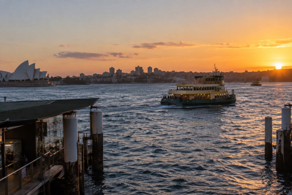 A ferry crossing Sydney Harbour at dusk with city lights beginning to glow on the shore