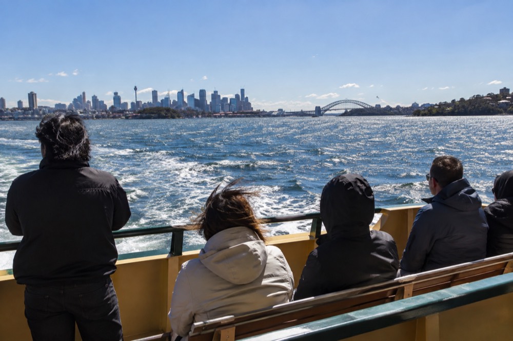 Passengers in warm waterproof jackets on a boat deck watching open ocean water