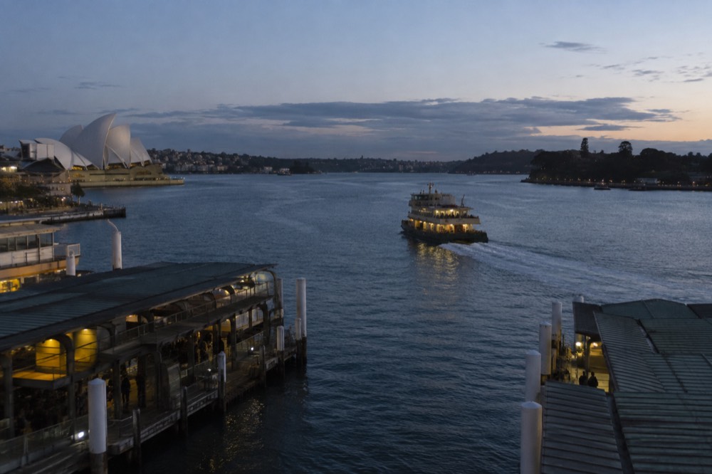 A ferry crossing calm harbour water toward a headland in winter light