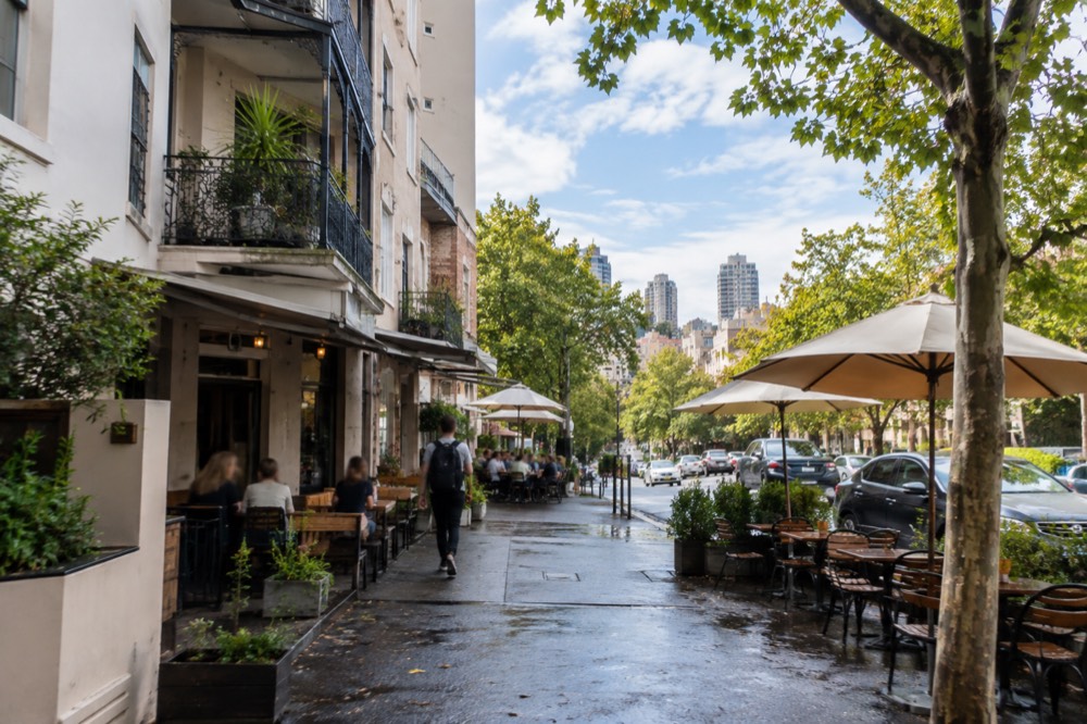 Backpacker hostel and café terrace on a tree-lined street in Kings Cross at midday