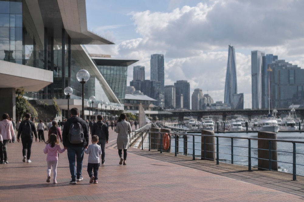 Families walking along the Darling Harbour waterfront promenade past a museum building