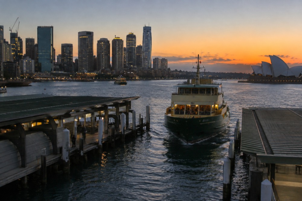 A Sydney ferry approaching a wharf with the city skyline behind it