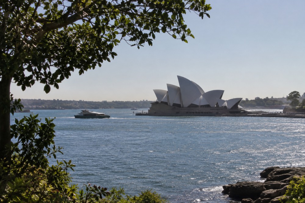 Sydney Opera House sails seen across sparkling harbour water under a summer sky