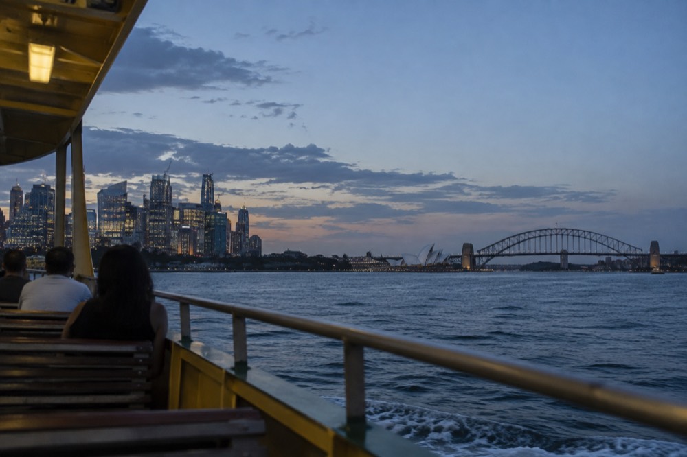 Ferry crossing open harbour water with city skyline behind