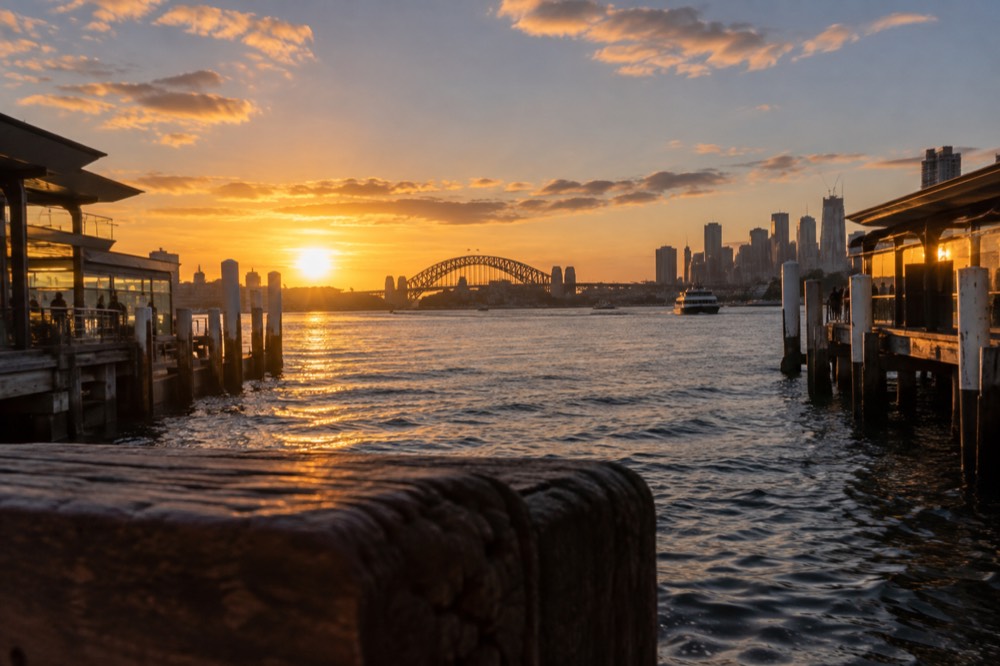 Sunset over the harbour with the bridge and city towers in golden light