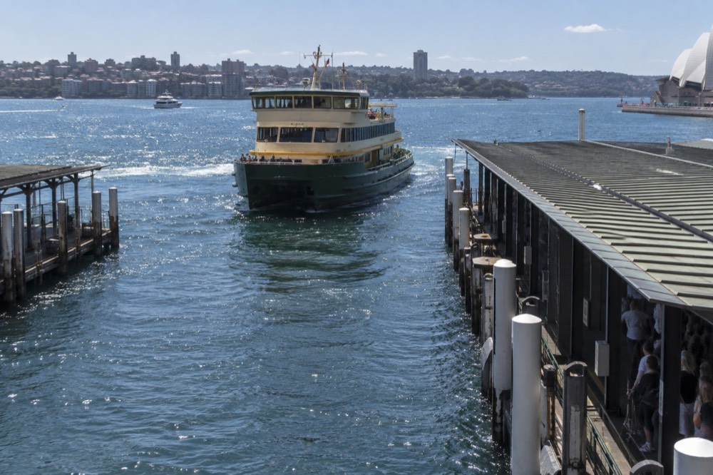 Green and cream Sydney ferry approaching a wharf on the harbour