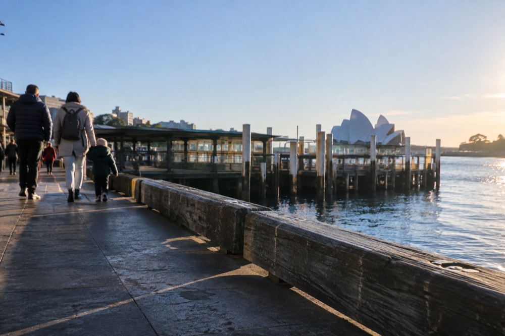 Families walking a coastal path above ocean pools on a clear winter morning